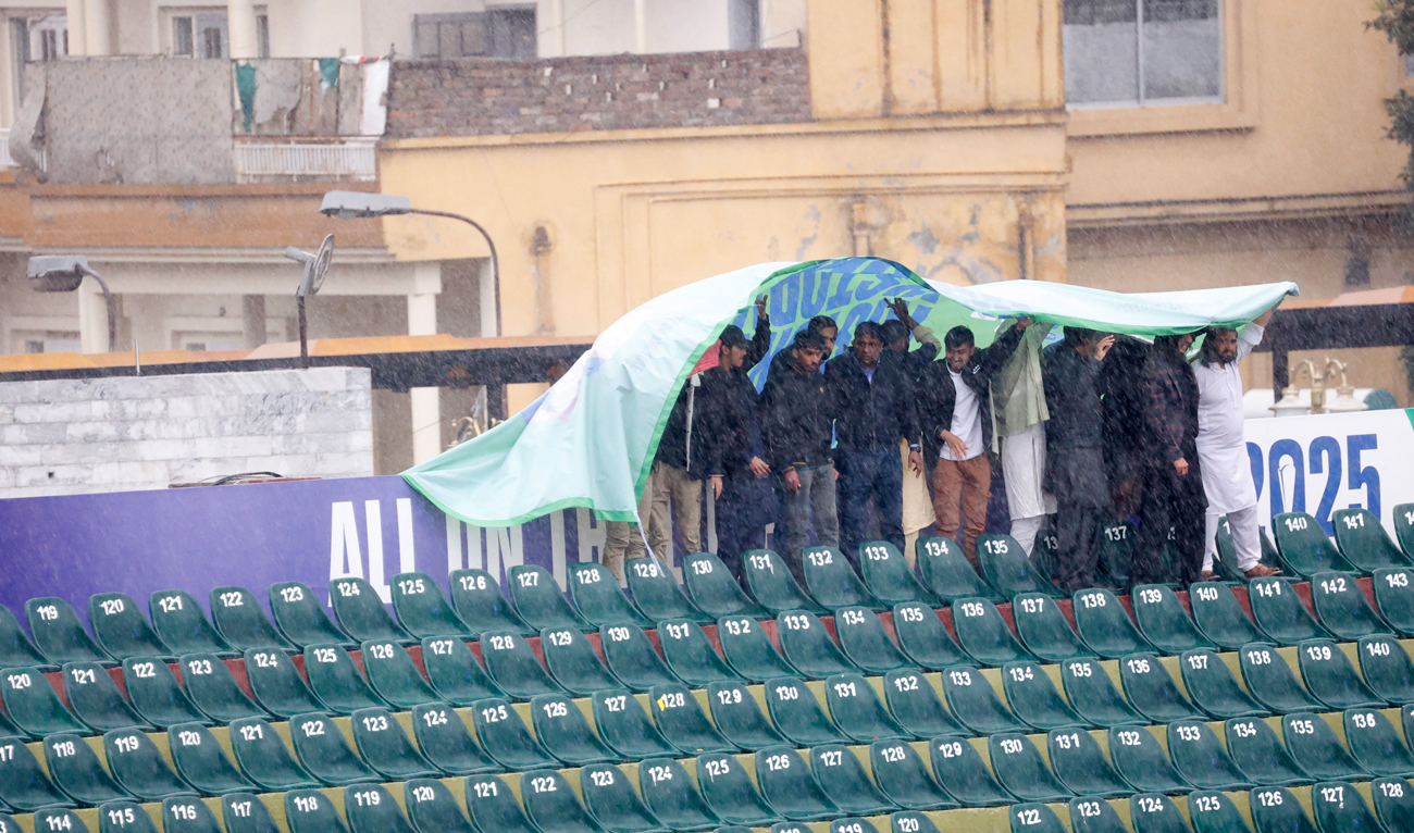 Fans use a banner as a cover in the stands as rain delays the start of play during the ICC Men’s Champions Trophy match between Pakistan and Bangladesh at the Rawalpindi Cricket Stadium in Rawalpindi, Pakistan on February 27, 2025. (REUTERS/File)