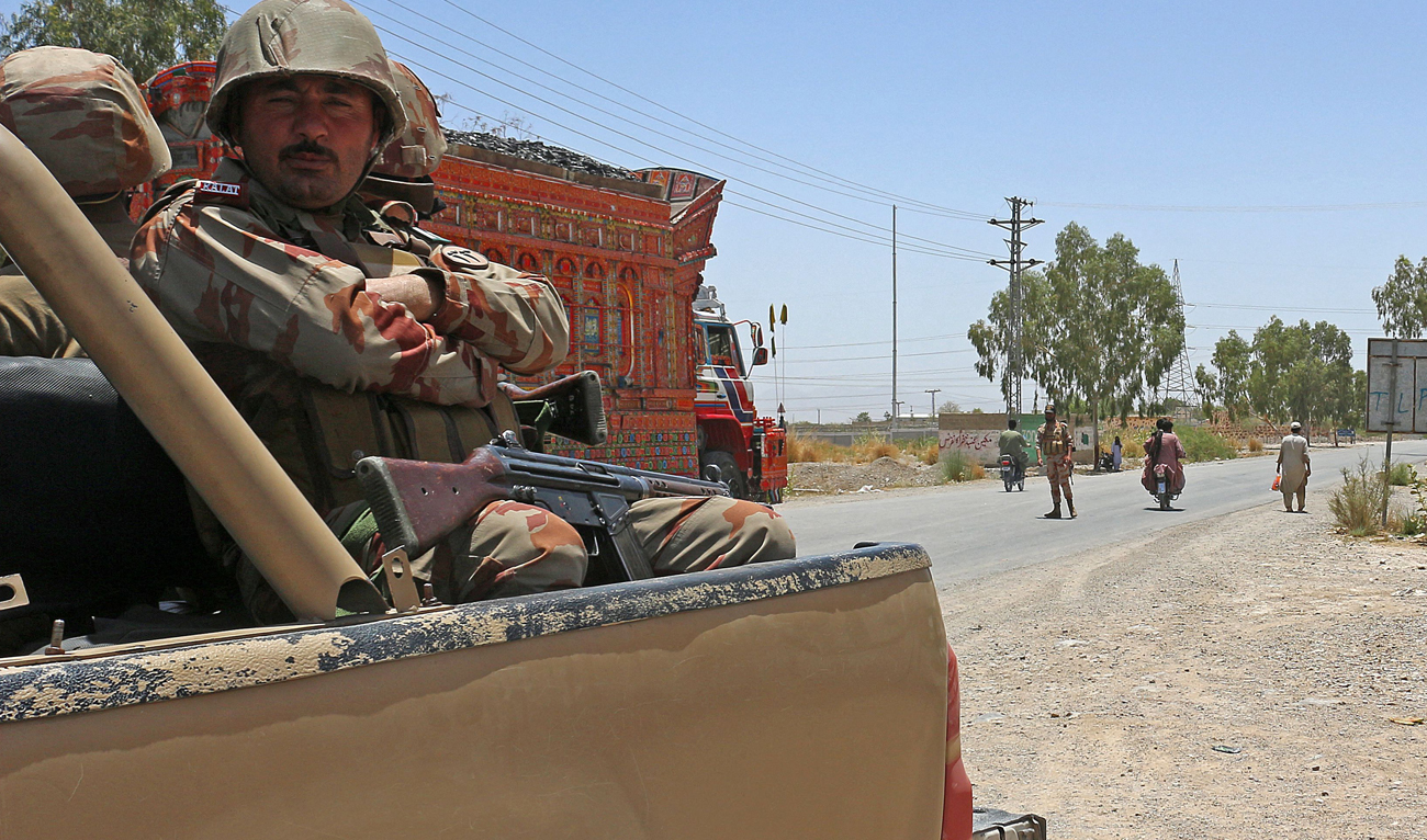Security personnel guard along a street near the site of a school bus bombing in the Khuzdar district of Balochistan province on May 21, 2025. (AFP)