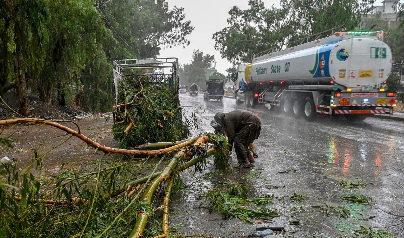 Workers remove a fallen tree from a road amid heavy rainfall in the Peshawar district of the Khyber Pakhtunkhwa province of Pakistan on May 27, 2025. (AFP)