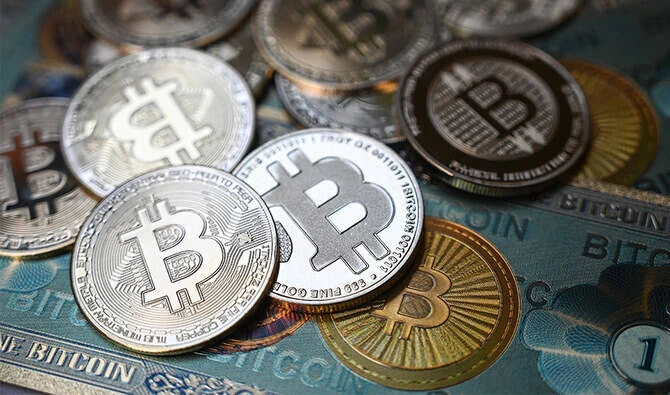This illustration photograph taken on July 19, 2021, in Istanbul, shows a physical banknote and coin imitations of the Bitcoin cryptocurrency. (AFP/File)