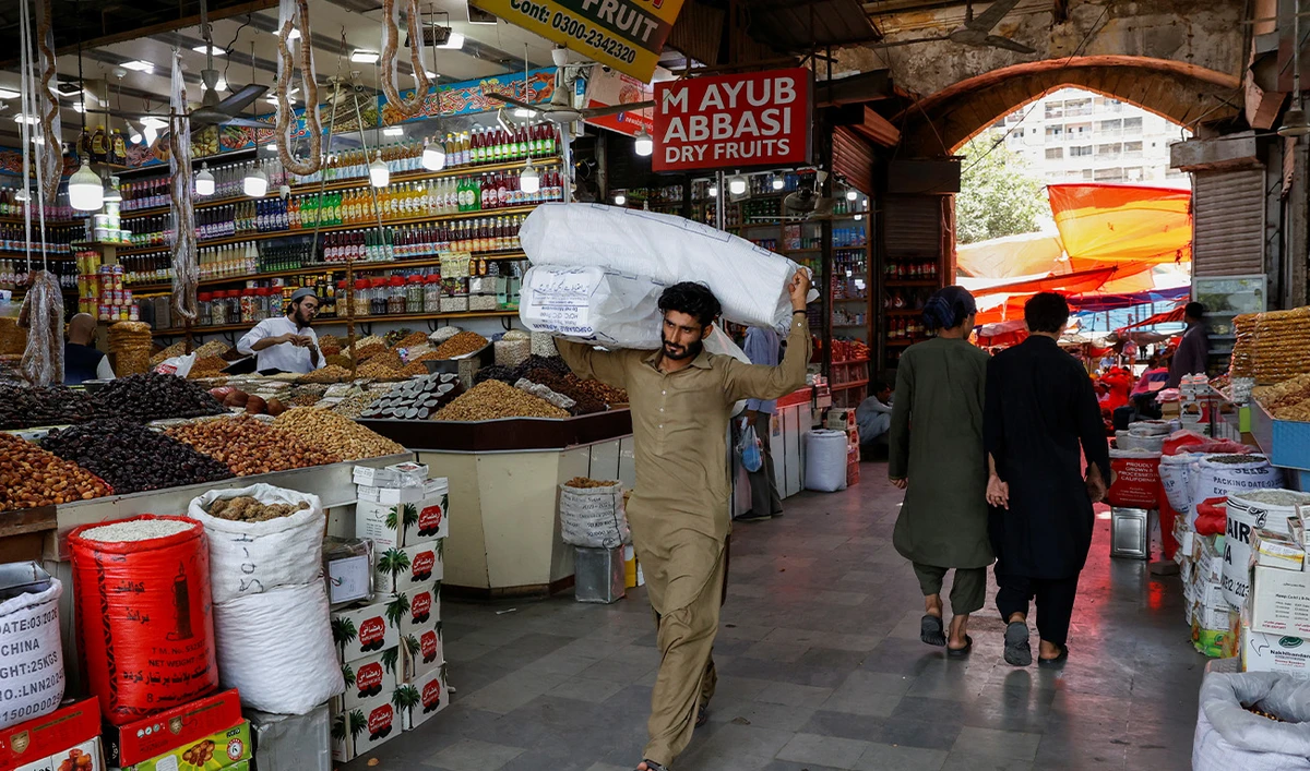 A man walks with sacks of supplies on his shoulder to deliver to a nearby shop at a market in Karachi, Pakistan on June 11, 2024. (Reuters/File)