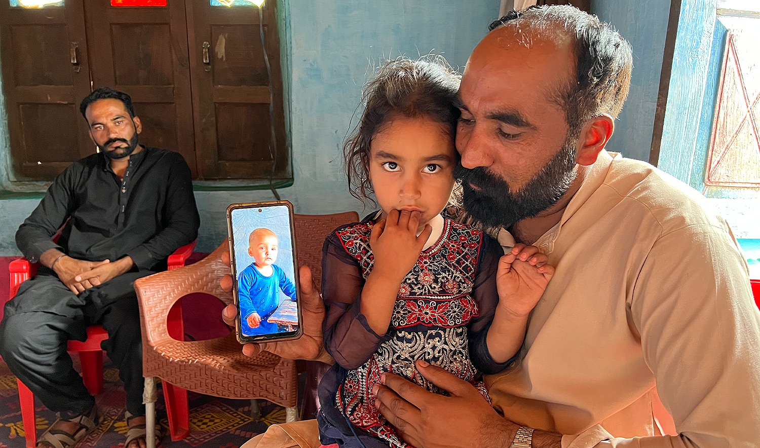 Wajid Kayani (right) shows a picture of his two-year-old daughter, Hadiya Wajid, on his mobile in Chafar village in the Poonch district of Pakistan-administered Azad Kashmir on May 23, 2025, who was killed by an Indian mortar shell on May 10. (AN photo)