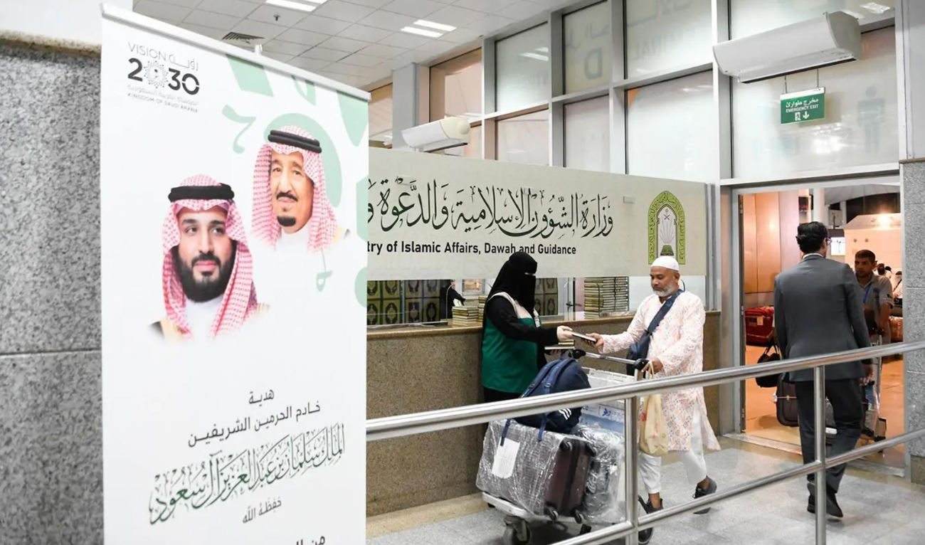 A female official from Saudi Ministry of Islamic Affairs, Dawah and Guidance hands a copy of the Holy Qur’an to departing Hajj pilgrims at the King Abdulaziz International Airport in Jeddah on June 11, 2025. (SPA)