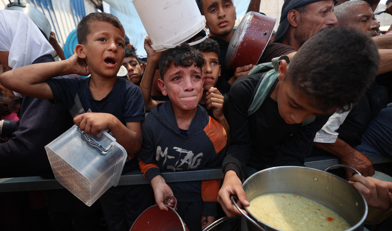 Palestinian children wait for food at a distribution point in Nuseirat, in the central Gaza Strip, on June 11, 2025. (AFP)