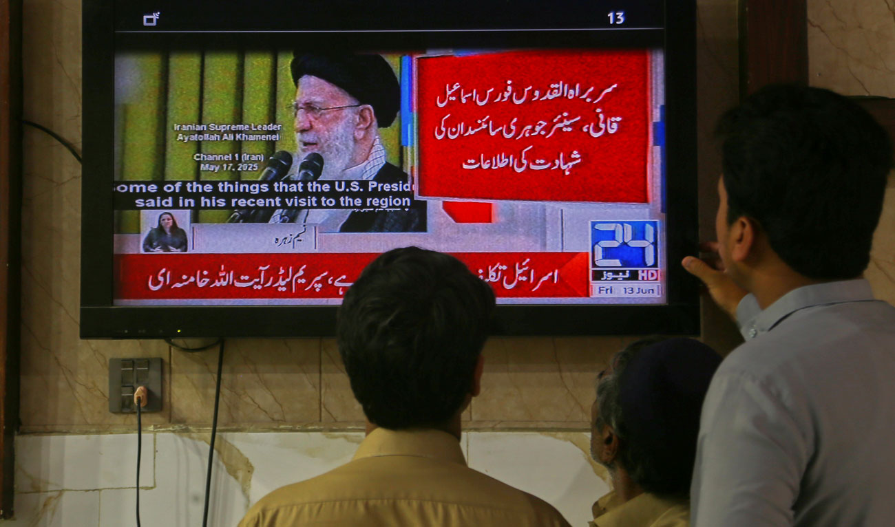 Pakistanis watch a news channel telecasting report about the Israeli attacks on Iran, in Peshawar, Pakistan on June 13, 2025. (AP)