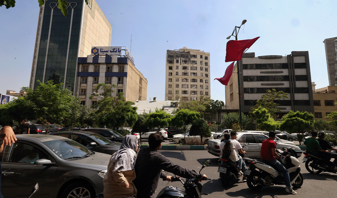Onlookers drive next to a building damaged in an Israeli strike on Tehran, Iran, on June 13, 2025. (AFP)