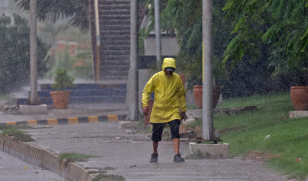 A man wears a rain jacket as he walks along a side walk during a rain in Karachi, Pakistan, on August 2, 2024. (REUTERS/File)