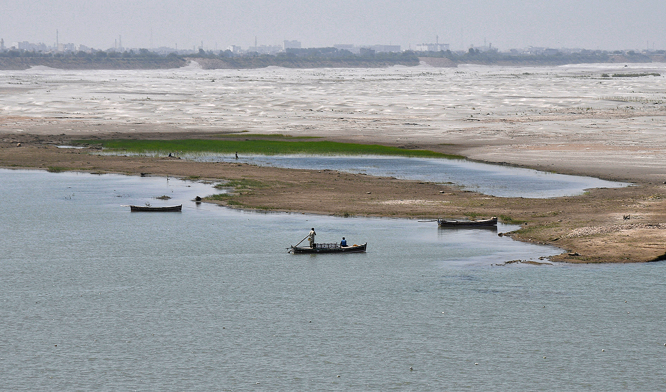 A man navigates a boat in the water next to the dry riverbed of the Indus River in Hyderabad, Pakistan, on April 25, 2025. (REUTERS/File)