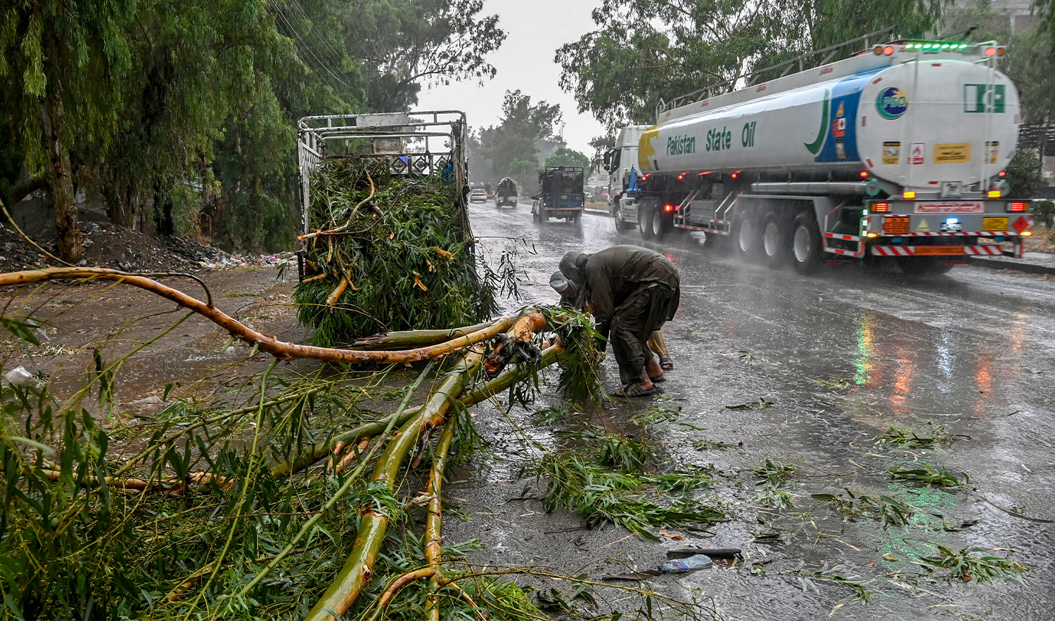 Workers remove a fallen tree from a road amid heavy rainfall in the Peshawar district of the Khyber Pakhtunkhwa province of Pakistan on May 27, 2025. (AFP/File)