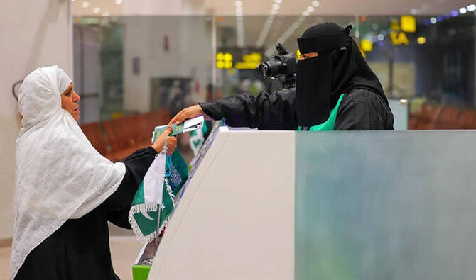 A Saudi officer hands a Pakistani pilgrim her passport at the Makkah Route immigration counter at Islamabad International Airport in Islamabad on April 29, 2025. (SPA/File)