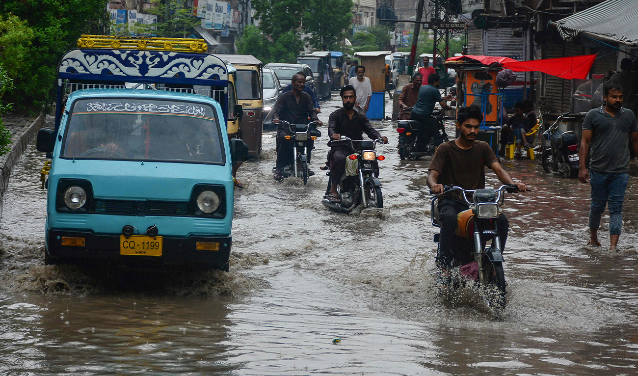 Commuters make their way through a flooded street following heavy rainfall in Hyderabad, Pakistan, on June 27, 2025. (AFP)