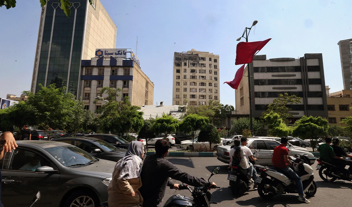 Onlookers drive next to a building damaged in an Israeli strike on Tehran, Iran, on June 13, 2025. (AFP)