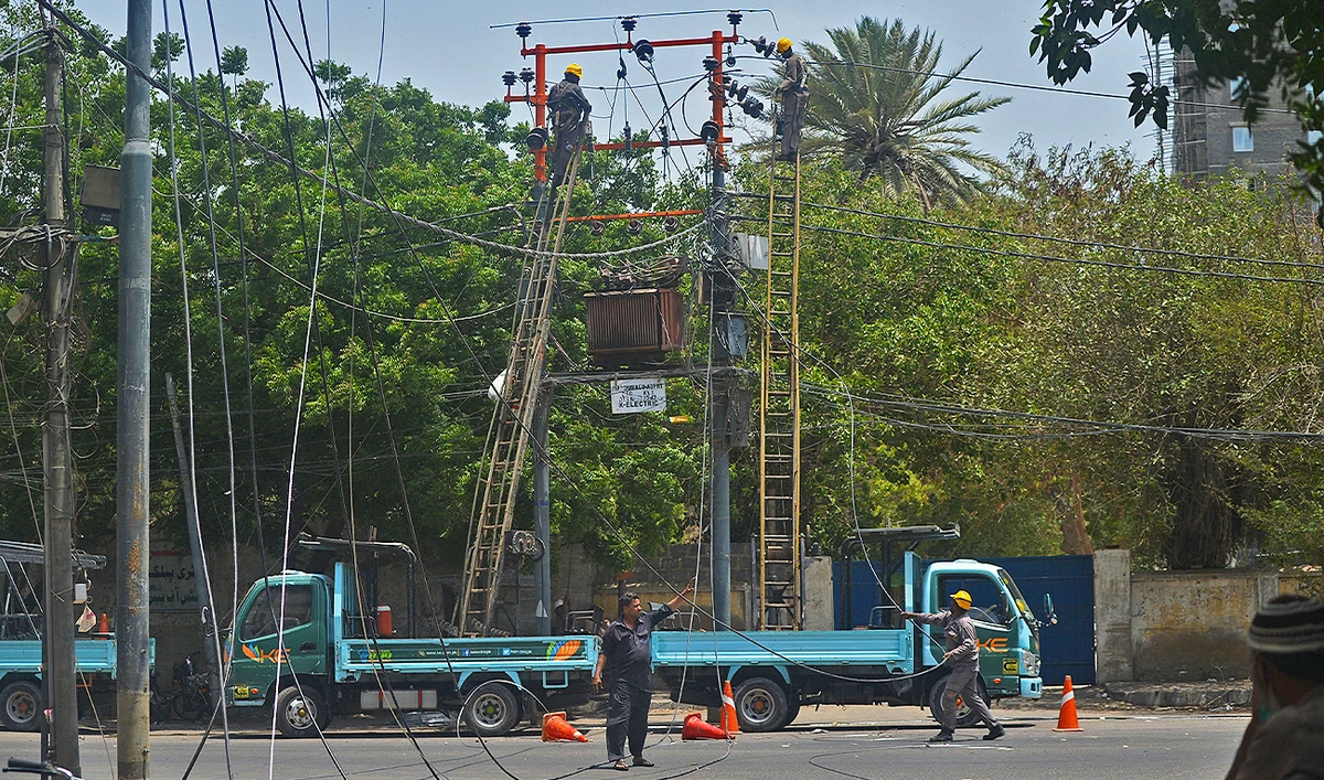 Men work on electric pylons along the roadside in Karachi on May 30, 2021. (AFP/File)
