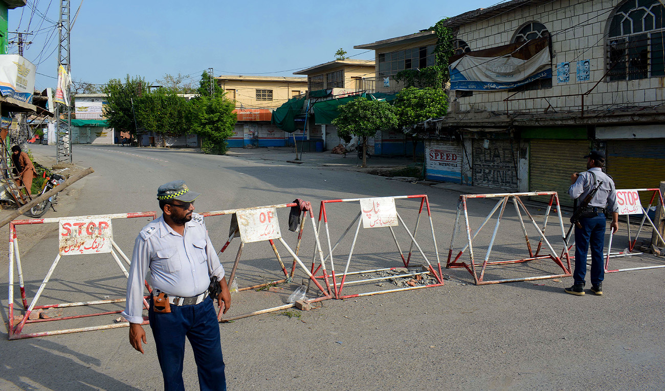 Policemen stand guard along a barricaded street near an army cantonment, a day after it was attacked by a militant suicide squad in Bannu on July 16, 2024. (AFP/File)