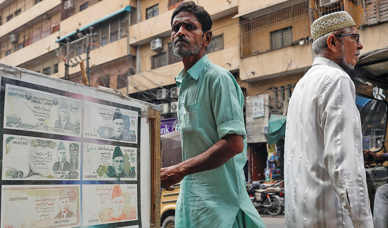 People walk past a sidewalk money exchange showcase, which is decorated with pictures of currency notes, in Karachi, Pakistan, on September 12, 2023. (REUTERS/File)