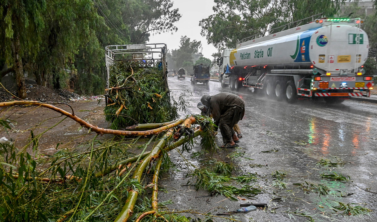 Workers remove a fallen tree from a road amid heavy rainfall in the Peshawar district of the Khyber Pakhtunkhwa province of Pakistan on May 27, 2025. (AFP/File)