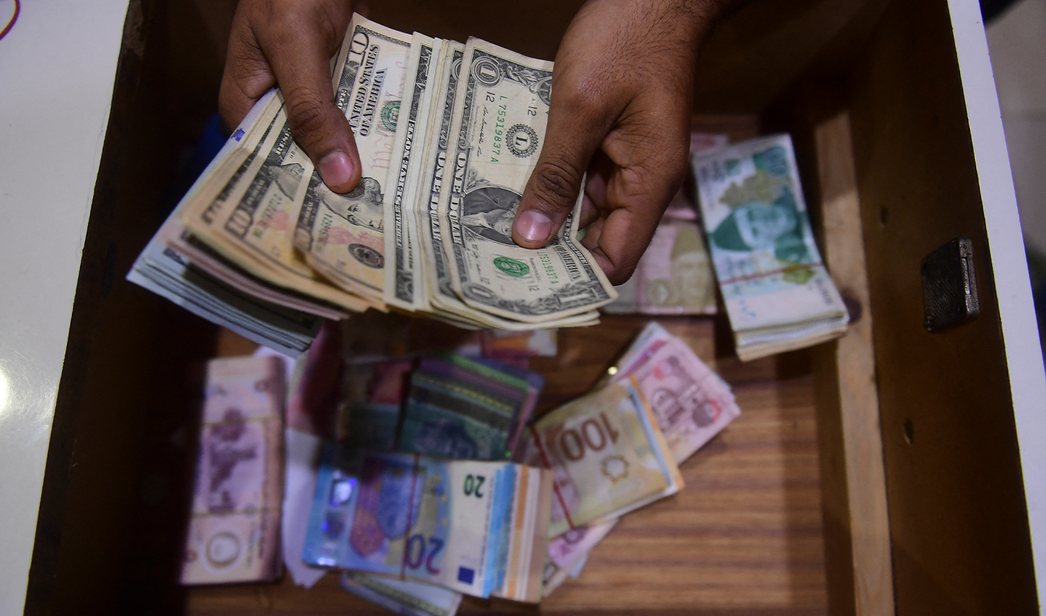 A dealer counts US dollars at a money exchange market in Karachi on January 27, 2023. (AFP/File)