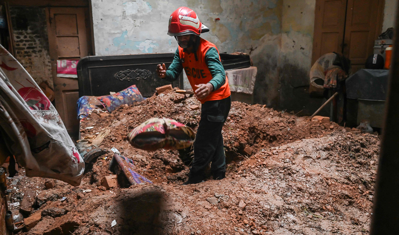 A rescue worker clears debris from a collapsed roof after heavy monsoon rains in Lahore, Pakistan, on July 10, 2025. (AFP)