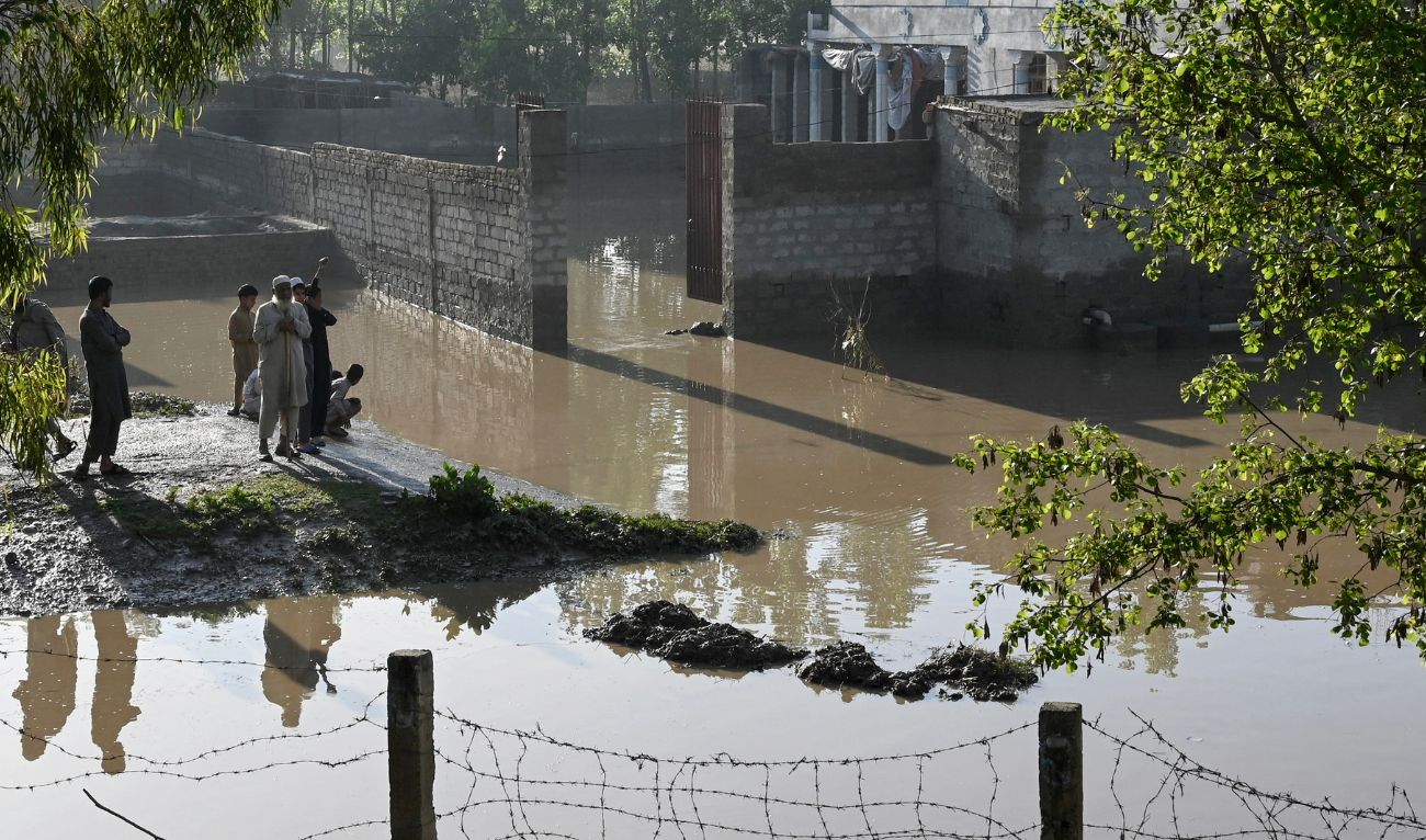 Residents stand near the flooded waters outside their homes following heavy rains in Charsadda district of Khyber Pakhtunkhwa province on April 17, 2024. (AFP)
