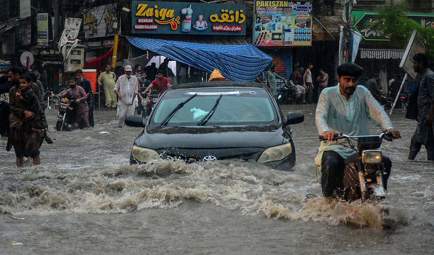 Commuters wade through a flooded street during heavy monsoon rains in Hyderabad, in Sindh province, on July 14, 2025. Monsoon rains in Pakistan have been linked to more than 110 deaths including dozens of children since they arrived in late June, according to government figures released on July 14. (AP)