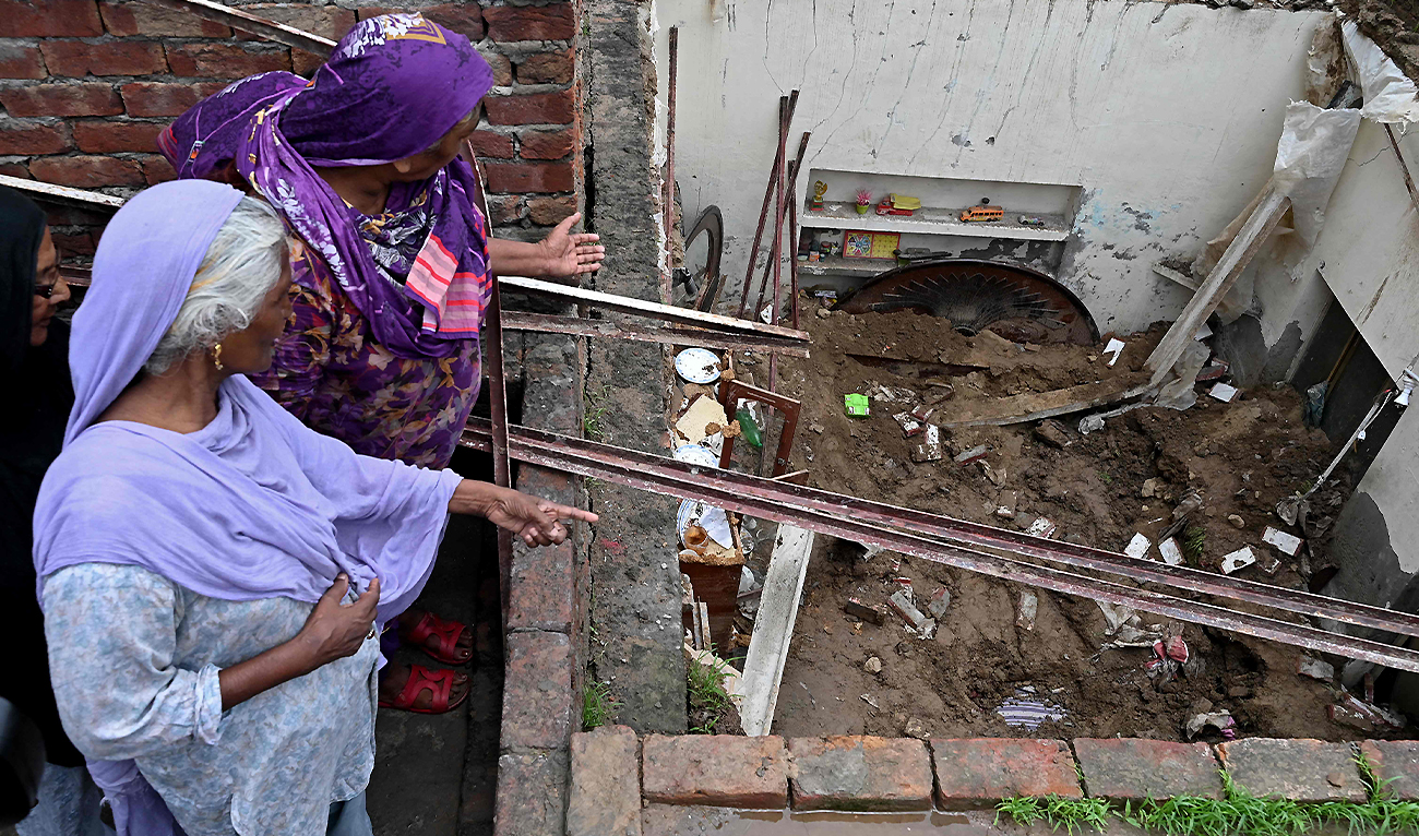 Neighbours look at the collapsed roof of a house during heavy monsoon rains in Lahore on July 16, 2025. (AFP)