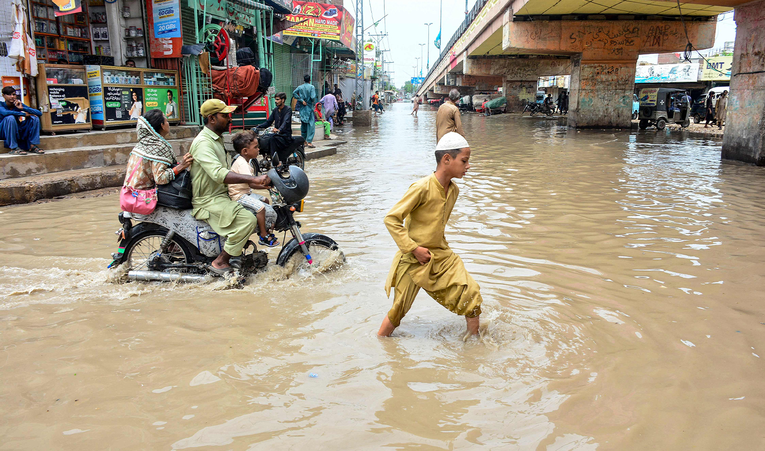 People wade through a flooded street after heavy monsoon rains in Hyderabad, Sindh province on July 20, 2025. (AFP)