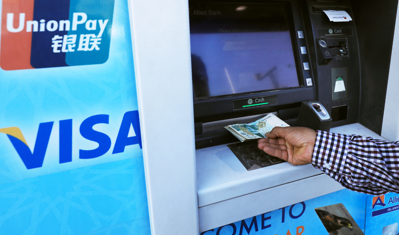 A man withdraws cash from an automated teller machine (ATM) in Peshawar, Pakistan on April 1, 2019. (REUTERS/File)