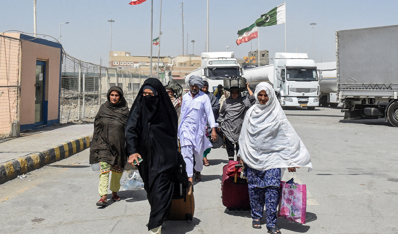 Pakistani Shiite pilgrims carrying their belongings walk across the Pakistan-Iran border after returning from Iran in Taftan, in Balochistan province, on June 19, 2025. (AFP/File)