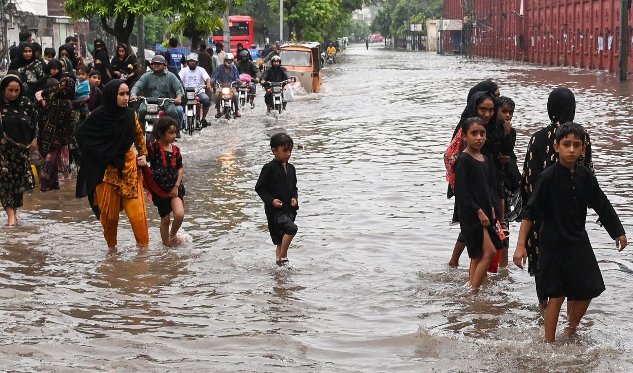 Commuters wade through a flooded street after heavy rainfall in Lahore on July 23, 2025. (AFP/ file)