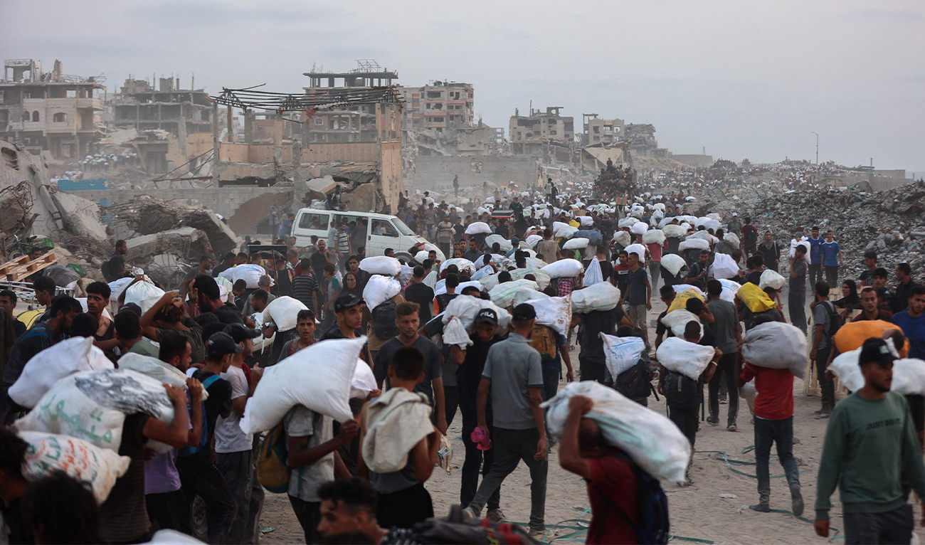 Palestinians bring back aid parcels they managed to procure as they walk on a coastal path west of Beit Lahia on July 29, 2025, after aid trucks entered the Israel-besieged Gaza Strip from the northern Zikim border crossing. (AFP)