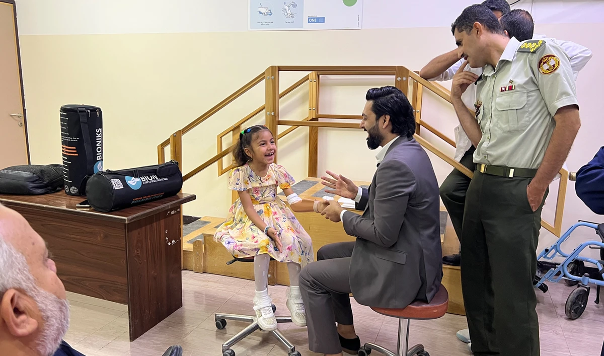 Anas Niaz, head of Pakistani health-tech startup Bioniks, tests a prosthetic limb as Sidra, a young girl from Gaza, smiles during a fitting session in Amman, Jordan, on July 2, 2025. Bioniks recently announced the successful fitting of its first prosthetic limb in Gaza for a girl injured in the ongoing Israel-Hamas war — marking a milestone in its broader mission to support amputees in the besieged territory. (AN Photo by Zainab Jamal)
