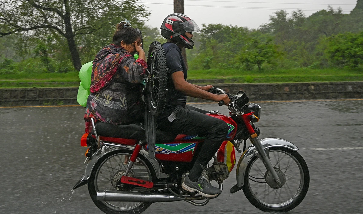 A motorcyclist rides along a street during rainfall in Islamabad on July 7, 2025. (AFP)