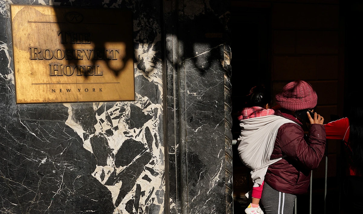 A migrant carrying a child speaks on the phone outside of The Roosevelt Hotel in midtown Manhattan in New York City, US, February 24, 2025. (Reuters/File)