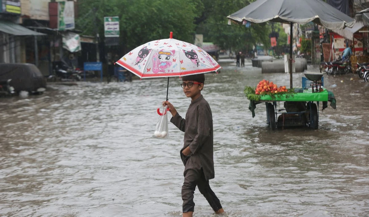 A Child holds an umbrella as he wades through a flooded street after a downpour in Lahore, Pakistan July 9, 2025. (REUTERS)