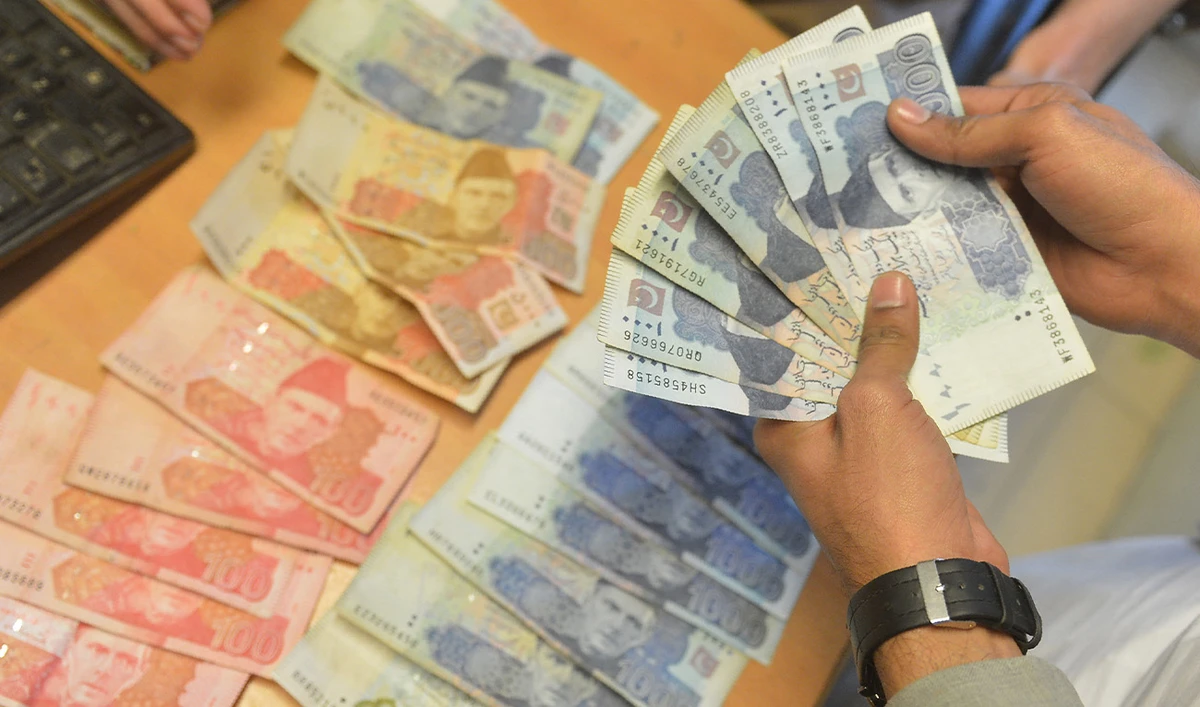 A money changer counts Pakistan's currency at a market in Karachi on January 6, 2023. (AFP/File)