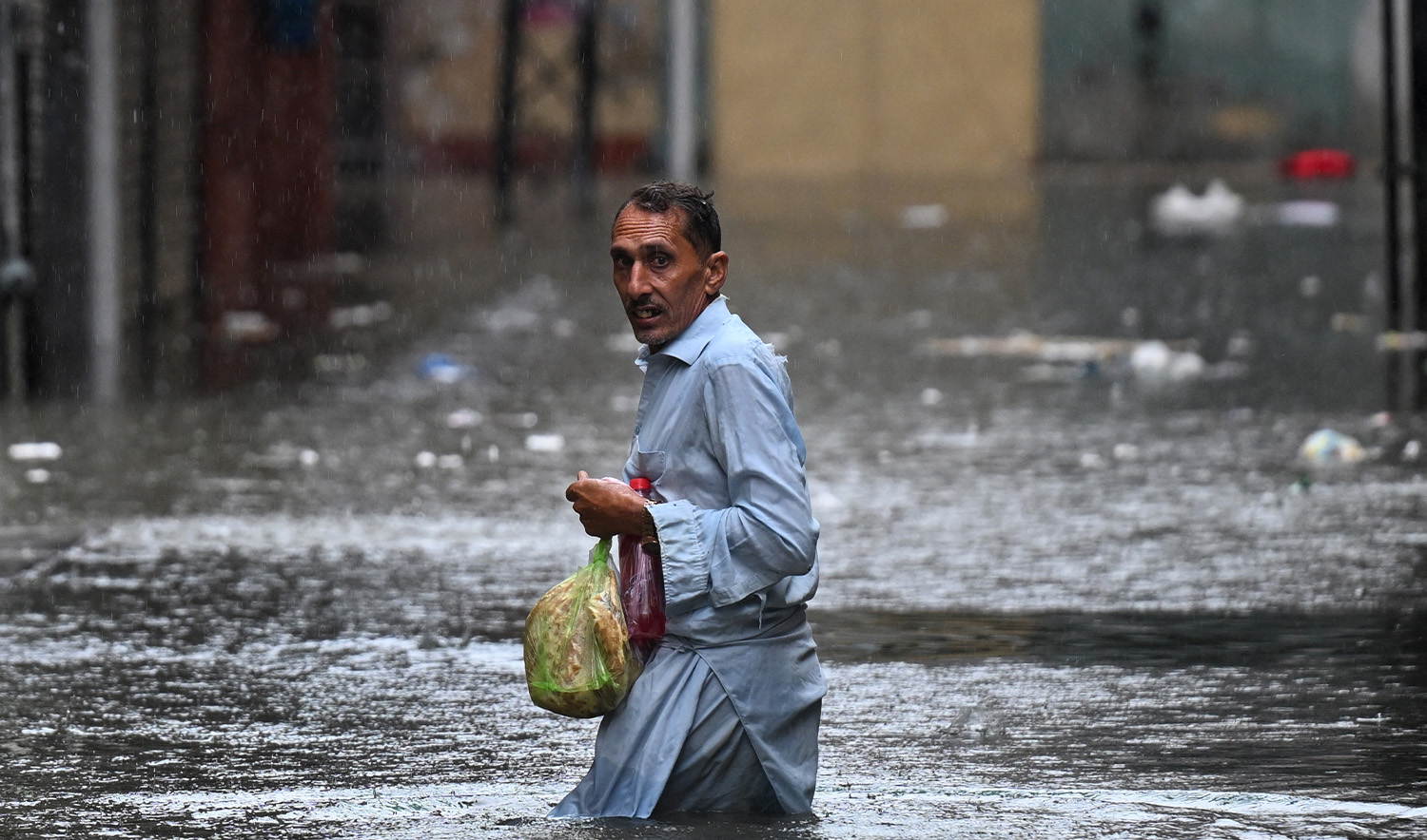 A man wades through a flooded street during heavy monsoon rains in Rawalpindi on July 17, 2025. (AFP)