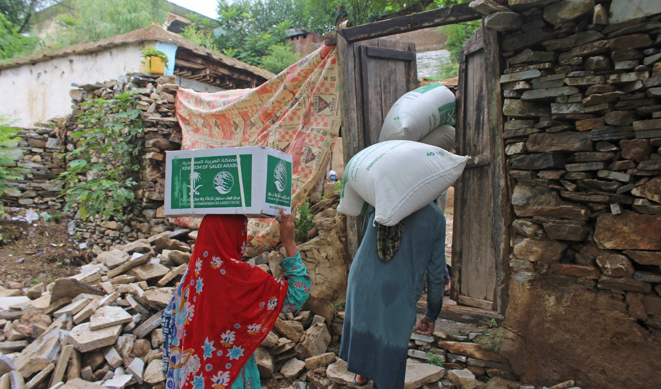 People carry ration bags provided by KSrelief in areas affected by natural disasters in Azad Jammu and Kashmir in a picture shared by KSrelief on August 5, 2025. (KSrelief)