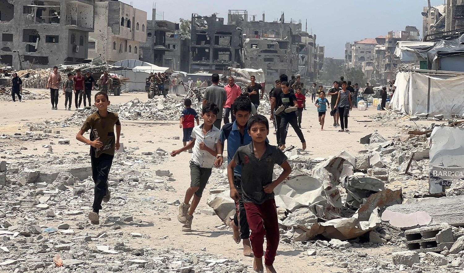 Palestinians run toward food parcels dropped by a military aircraft in Jabalia in the northern Gaza Strip on August 9, 2025. (AFP)