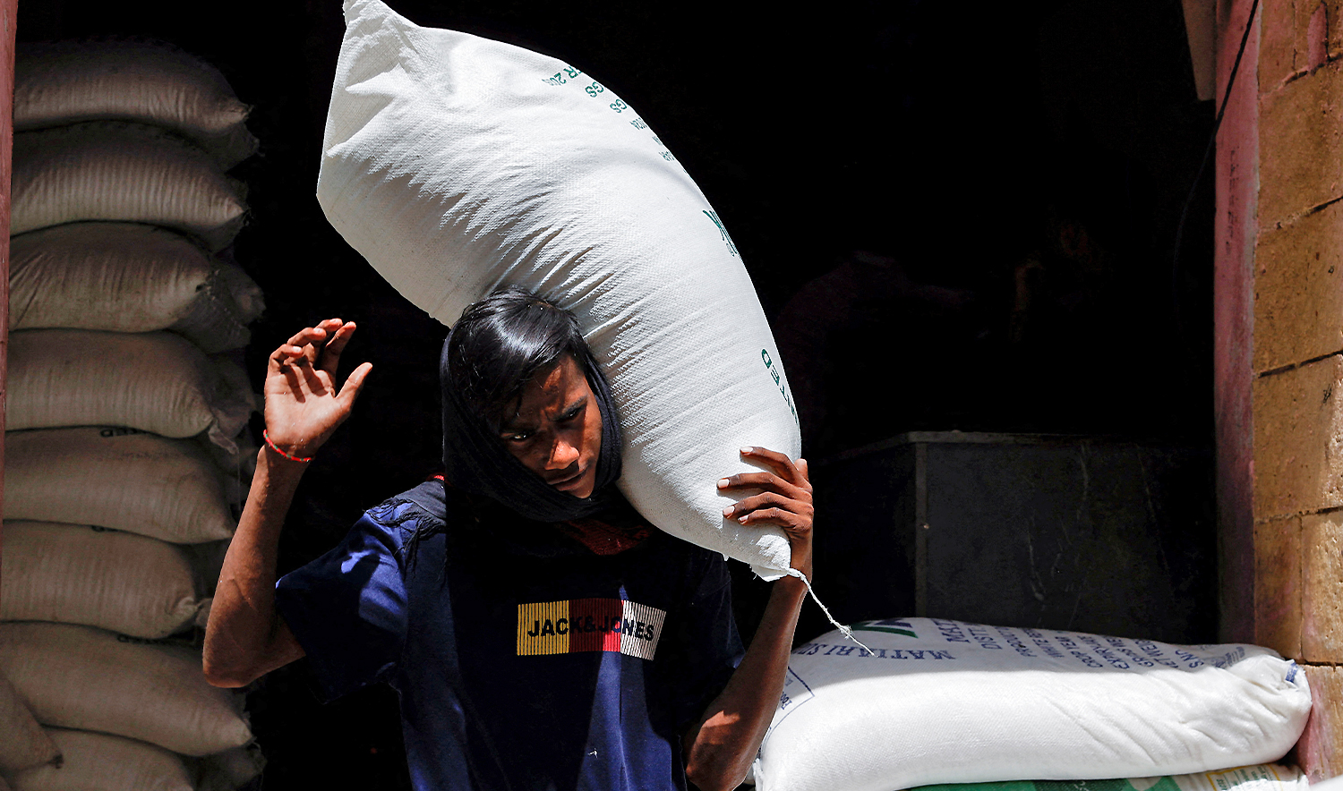A labourer carries a sack of sugar while loading on a cart at a wholesale food and grain market in Karachi, Pakistan, on June 12, 2024. (REUTERS/File)