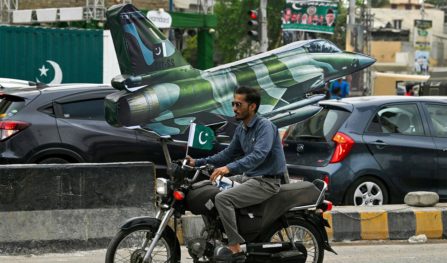 A motorcyclist rides past a Pakistani JF-17 fighter jet model displayed along a road in Karachi on August 13, 2025, on the eve of the country's independence day celebrations. (AFP)