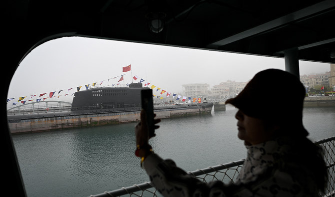 This picture taken during a media tour organised by the Chinese People's Liberation Army Navy (PLAN) to mark its 75th founding anniversary, shows a woman taking pictures of a submarine at the PLA Naval Museum in Qingdao, China's Shandong province on April 23, 2024. (AFP/File)