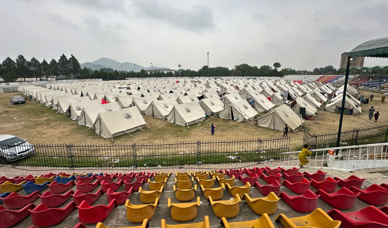 Internally Displaced People (IDPs), who fled their homes following a targeted operation by security forces against militants, walk through a makeshift camp set up in a sports complex in Khar, the main town of Bajaur, a district in northwestern Pakistan near the Afghanistan border on August 13, 2025. (AFP)
