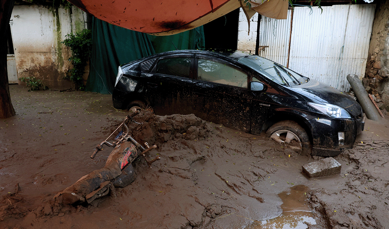 A motorcycle lies partially covered by a thick layer of mud next to a stranded vehicle, following a storm that caused heavy rains and flooding in Pacha Kalay Bazar, in Buner district, in Khyber Pakhtunkhwa province, Pakistan, August 17, 2025. (Reuters)