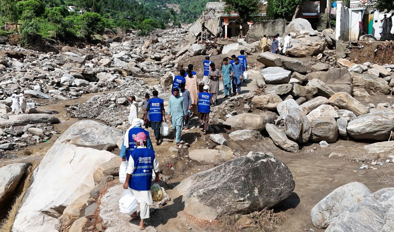 In this aerial picture, volunteers carry aid for residents, after flash floods hit Buner district in northern Pakistan's mountainous Khyber Pakhtunkhwa province on August 18, 2025. (AFP)