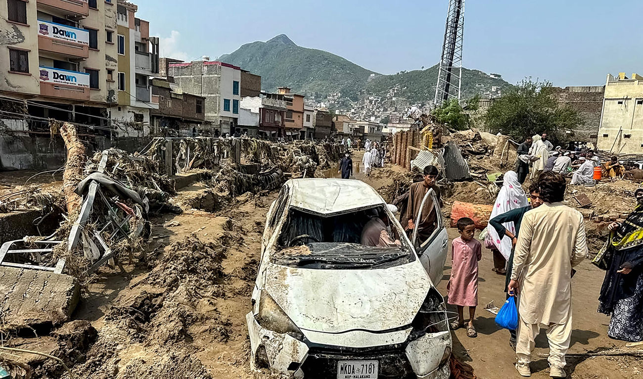 People gather near a damaged vehicle and scattered debris after the road washed out following a flash flood in Mingora, the main city of Swat Valley, in monsoon-hit northern Pakistan’s mountainous Khyber Pakhtunkhwa province on August 16, 2025. (AFP/File)