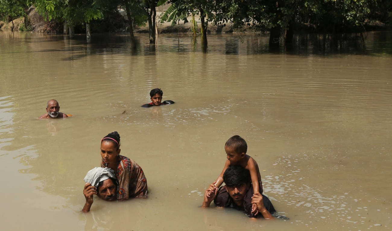 Villagers wade through flooded water following heavy rains in Ehsan Pur village, Kot Addu district of Punjab province on August 21, 2025. (AFP)