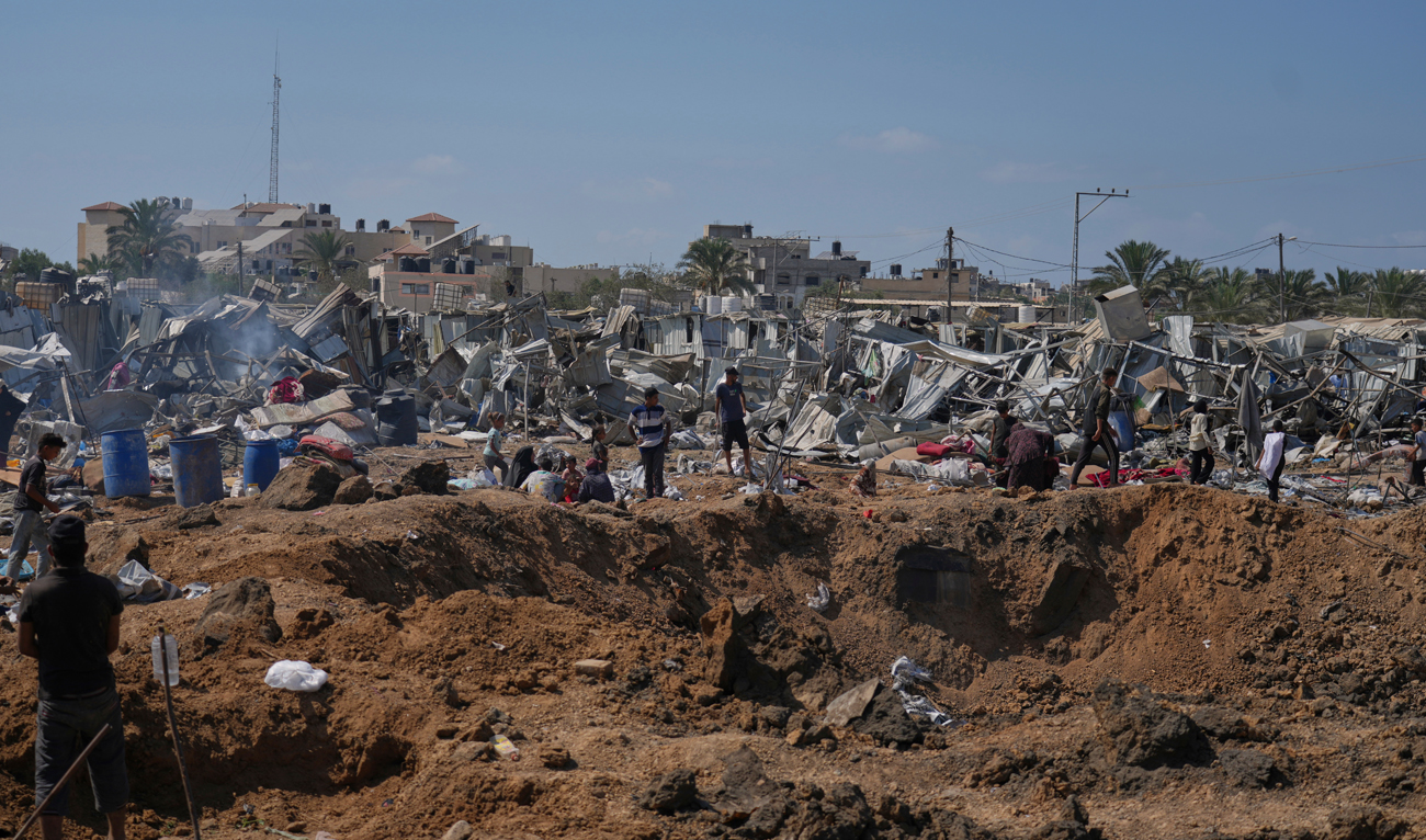 Palestinians stand on the edge of a crater after Israeli military strikes in a tent camp for displaced people near Al-Aqsa Hospital, in Deir al-Balah on August 21, 2025. (AP)