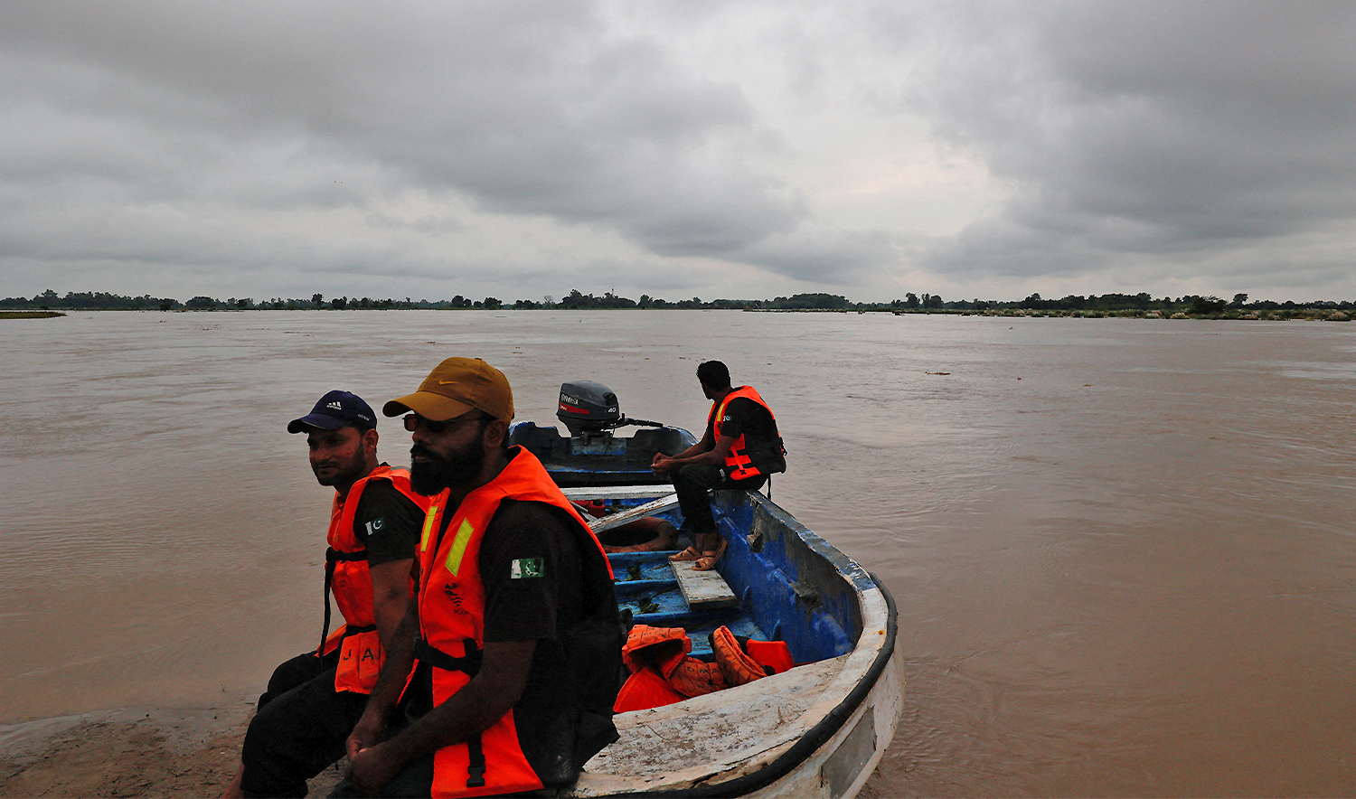 Members of the Rescue 1122 team sit on a boat with the monsoon rain clouds in the background, as they are waiting for residents to evacuate, due to the monsoon rains and rising water level of the Sutlej River, in Ghatti Kalanjar village near the Pakistan-India border in Kasur district of the Punjab province, Pakistan, on August 24, 2025. (REUTERS)