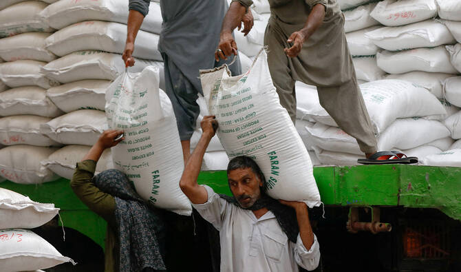 Laborers unload bags of sugar from a delivery truck to a wholesale market in Karachi, Pakistan, on May 24, 2023. (Reuters/File)