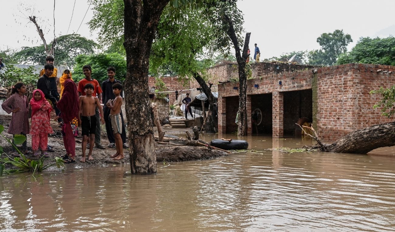 Villagers stand outside their houses, partially submerged in floodwaters, after heavy rainfall in the Haqu Wala village at Kasur district on August 24, 2025. (AFP/ file)